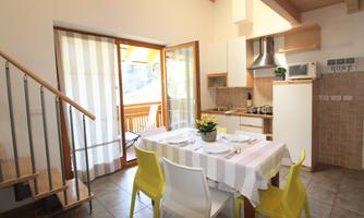 A modern kitchen with a dining area and large windows. The furniture is designed to be bright and welcoming.