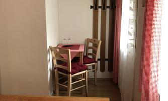 A cozy room with a bed and a small table. There are two chairs and a television on the wall.