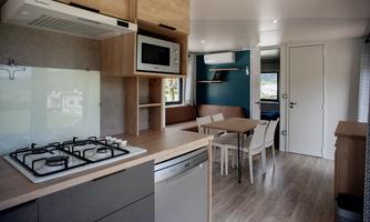 A modern kitchen with wooden surfaces and a dining table. The space feels bright and inviting.