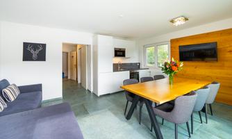 A modern and bright apartment with a cozy dining area. The table is decorated with a bouquet of flowers and there is an open kitchen area.