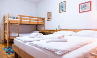 A cozy bedroom with a double bed and a bunk bed. The walls are decorated with small pictures.