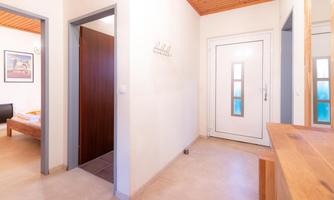 A bright hallway with an entrance door and wooden details. On the left side, there are two doors that lead to other rooms.