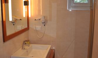 A modern bathroom with a sink and a large mirror. There is bright lighting and a window that lets in natural light.