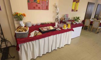 A set table with various dishes and drinks. In the foreground, baskets of bread, snacks, and drinks are arranged on red cloth.