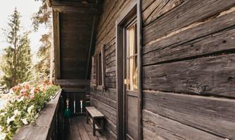 A rustic wooden balcony overlooking blooming plants. The atmosphere is cozy and inviting.