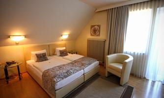 A cozy bedroom with two single beds and a modern armchair. Plenty of natural light flows through the window.