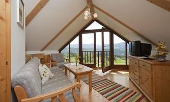 A cozy apartment in the attic with wooden details. Large windows offer a view of the landscape.