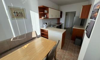 A bright kitchen with a dining area and modern furniture. Kitchen utensils are on the countertop, and a small table invites you to eat.
