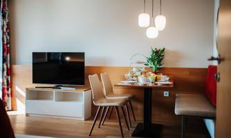 A cozy living area with a television and a dining table. The table is set with snacks and a vase of flowers.