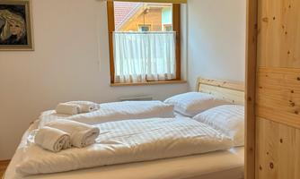 A cozy bedroom with a double bed and light wood. The windows are fitted with yellow roller blinds and curtains.