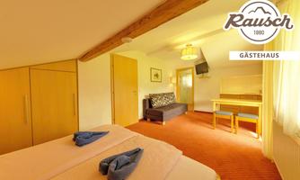 A cozy room with a double bed and a seating area. The bright decor creates an inviting atmosphere.