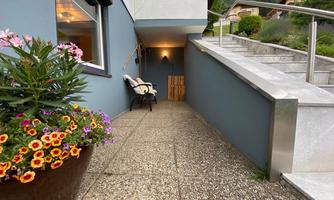 An inviting path with a blue wall, a seating area, and colorful flowers. The surroundings appear calm and well-maintained.