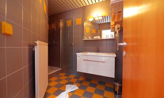 A modern bathroom with gray tiles and colorful accents. The furnishings include a sink, a mirror, and a shower.