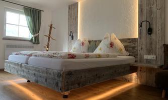 A modern bedroom with a wooden bed and cozy pillows. The warm lighting creates an inviting atmosphere.