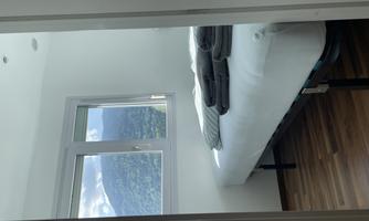A cozy bedroom with a bed and fresh towels. The window offers a view of the mountains.
