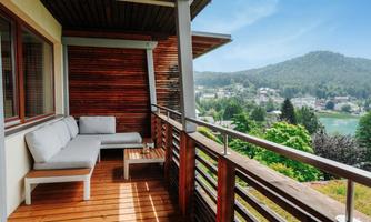 A beautiful balcony with a cozy seating area and a view of a green landscape. In the background, hills and a small village can be seen.
