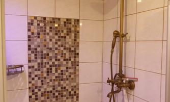Shower with large rainfall shower head and hand shower, white wall tiles and vertical mosaic panel.
