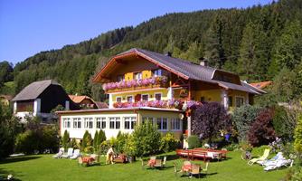 A charming yellow house with blooming window boxes and a large lawn. Surrounded by trees and a peaceful landscape, it offers an inviting atmosphere.
