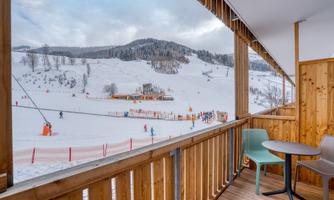 A beautiful view from a terrace of a snowy mountain landscape. Skiers are active on the slopes and the atmosphere is calm and inviting.
