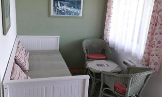 A cozy room with a white bench and two chairs. The window lets in plenty of light and the room is friendly designed.