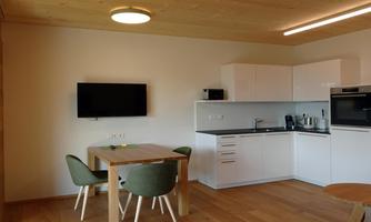 A modern kitchen with a dining area and comfortable chairs. The room is bright and cheerfully designed.