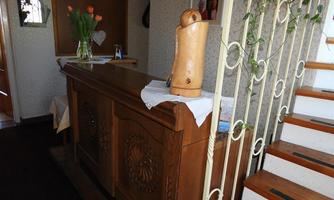 An inviting entrance area with a wooden counter and a vase of fresh flowers. In the background, a staircase leading upwards is visible.