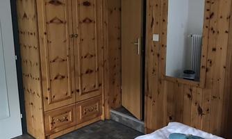 A cozy room with wooden paneling, a large wardrobe, and a mirror. Two beds are neatly decorated with blue towels.