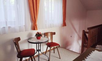 A cozy area with a small table and two chairs. Bright curtains hang in front of a window.