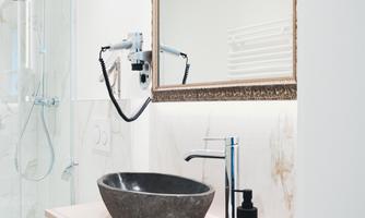 A modern bathroom with an elegant stone hand wash basin and a large mirror. The decor is minimalist and stylish.
