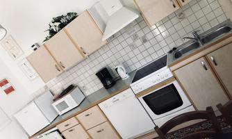 A modern kitchen with light wooden cabinets and white appliances. The space is tidy and well-lit.