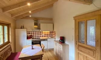 A cozy kitchen with wooden beams and a large table. The walls are light and the decor is modern and inviting.