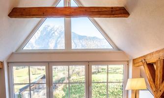 A cozy interior with a large window that looks out onto the mountains. The wooden beams give the room a rustic charm.