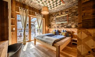 A cozy room with wooden paneling and large windows. The bed is inviting, and the decor exudes rustic elegance.