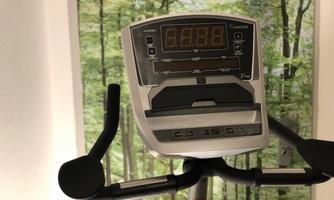 A modern training device with a digital display. In the background, there is an image of a forest.