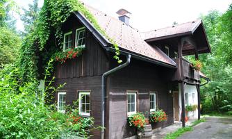 A charming wooden house surrounded by lush greenery. Flowers herald hospitality and a connection to nature.