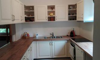 A modern kitchen with white cabinets and wooden countertops. It is well-organized and has space for various kitchen appliances.