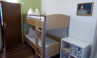 A cozy room with a loft bed and a dresser. The walls are painted in soft colors, and there is a small picture frame on the wall.
