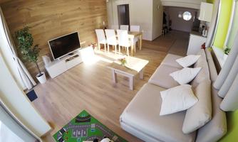 A modern living room with a cozy couch and a television. The room is bright and inviting, with a table and chairs in the dining area.
