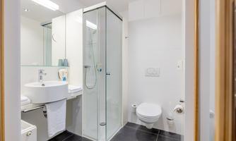 A modern bathroom with a shower, a sink, and a toilet. The walls are light and the floor is dark, creating a nice contrast.