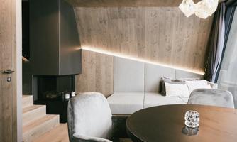 A modern and stylish living room with a wooden ceiling and soft lighting. The round table is elegant and invites you to linger.