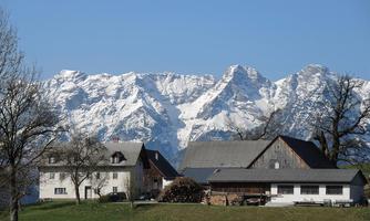 A picturesque mountain village with snow-covered mountains in the background. The landscape is clear and sunny, ideal for relaxation in nature.