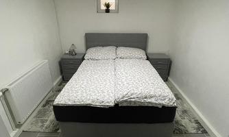 A cozy bedroom with a double bed and modern furniture. The room is bright and lovingly decorated, with a rug and a plant.