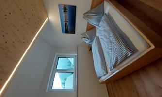 A cozy bedroom with a double bed and checkered bedspreads. The room has a window with a view outside and a modern, bright atmosphere.