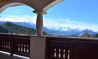 A beautiful view of the mountains with a blue sky. The balcony in the foreground has an elegant wooden cladding.