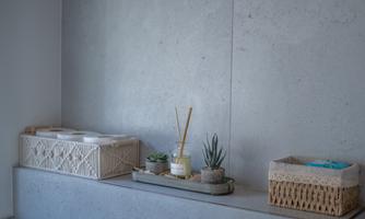 A modern room with a gray wall and a decorative shelf. On the shelf, there are some plants and decorative baskets.