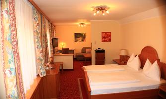 A comfortable hotel room with two beds, a television, and a table.  
The walls are painted in warm colors, and large windows let in plenty of light.
