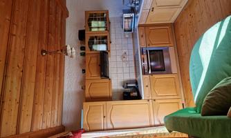 A bright kitchen with wooden cabinets and a cozy sofa. There are modern appliances and plenty of daylight.