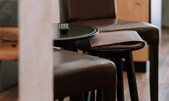 Two brown chairs and a small table are in a modern room. The floor is made of wood and the decor appears minimalistic.