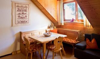 A cozy dining area with wood paneling and a large window. The table is surrounded by a small decorative object and chairs.
