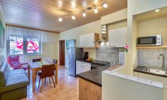 A modern kitchen with a dining area and comfortable seating. The room is bright and welcoming.